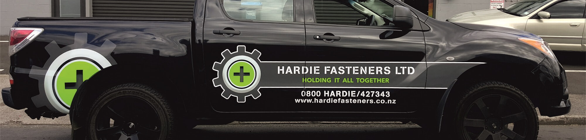 Black ute with Hardie Fasteners vehicle graphics in brand green