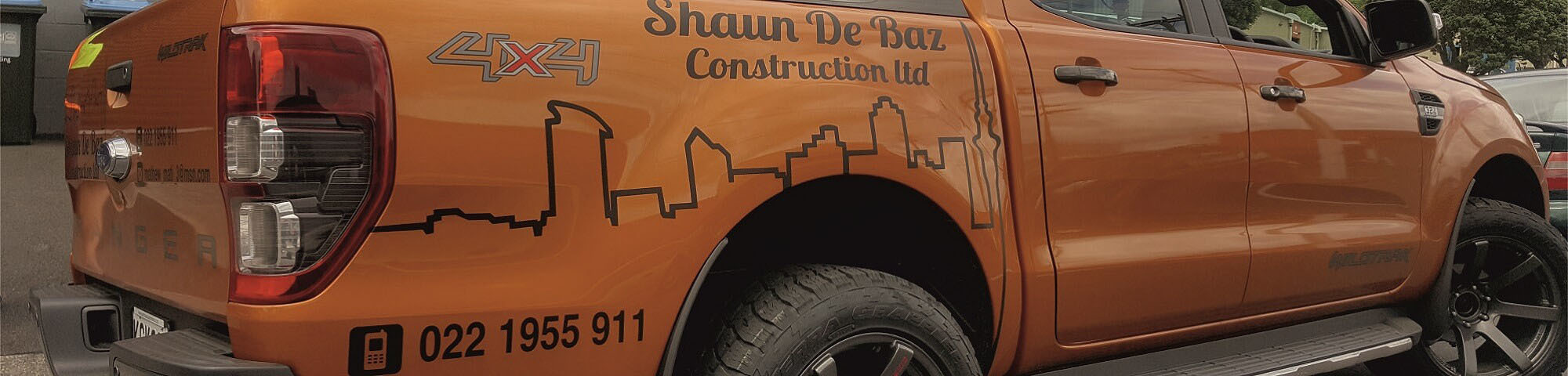 Orange Shaun De Baz Construction ute with full vehicle wrap and skyline graphic